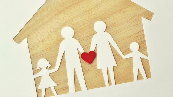Una famiglia di carta su una casa di legno, con in mano un cuore per rappresentare l'amore, il supporto e l'aiuto dell'ADHD