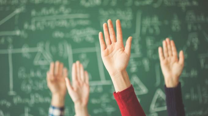 Gli studenti hanno sollevato il bordo di gesso verde delle mani in aula