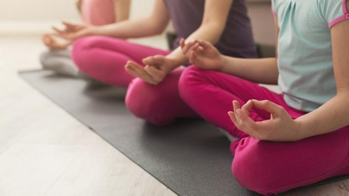 Il primo piano delle mani delle figlie e della madre che fanno l'yoga si esercita e che allunga a casa. Salute, sport, concetto di svago